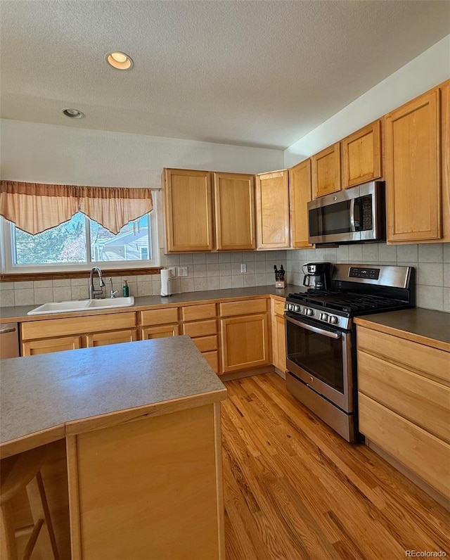 kitchen featuring sink, light hardwood / wood-style flooring, stainless steel appliances, tasteful backsplash, and light brown cabinetry