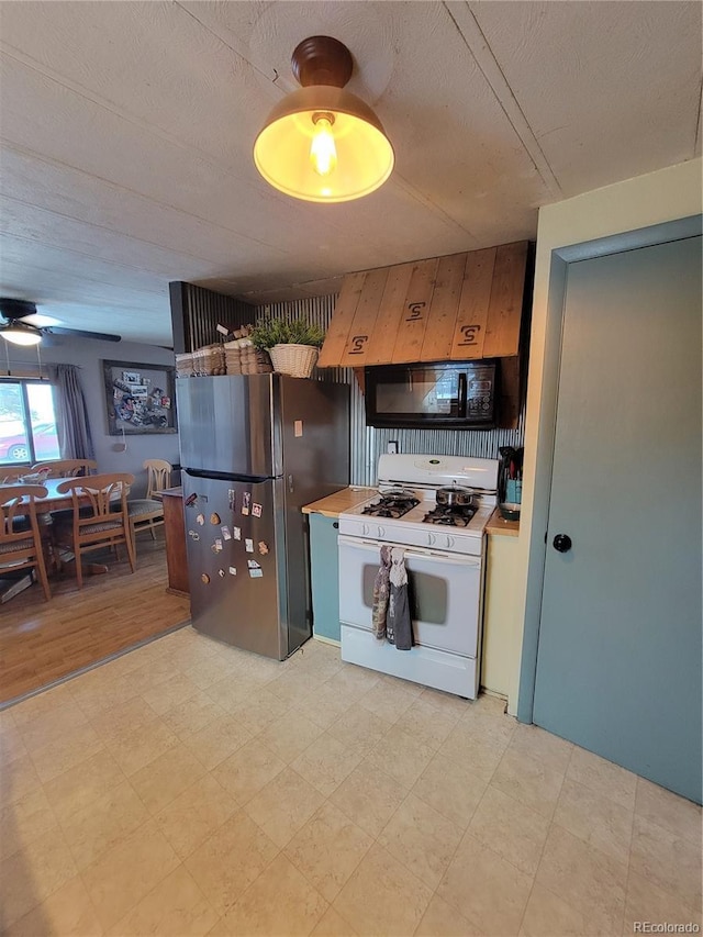 kitchen featuring stainless steel refrigerator, premium range hood, white range with gas stovetop, and a textured ceiling