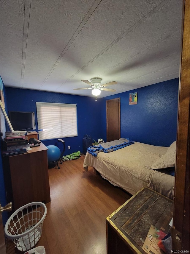 bedroom with hardwood / wood-style flooring, ceiling fan, and a textured ceiling