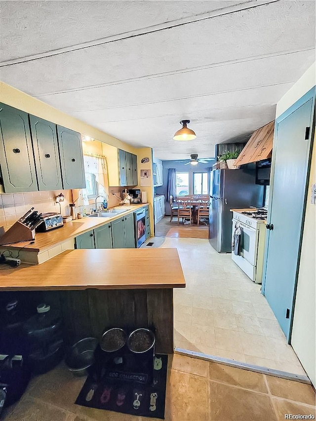 kitchen featuring sink, kitchen peninsula, and white gas range oven