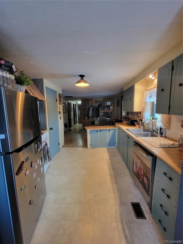 kitchen with visible vents, a peninsula, freestanding refrigerator, a sink, and light countertops