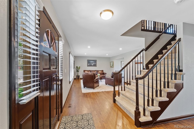 entryway with light wood-style floors, recessed lighting, stairs, and baseboards