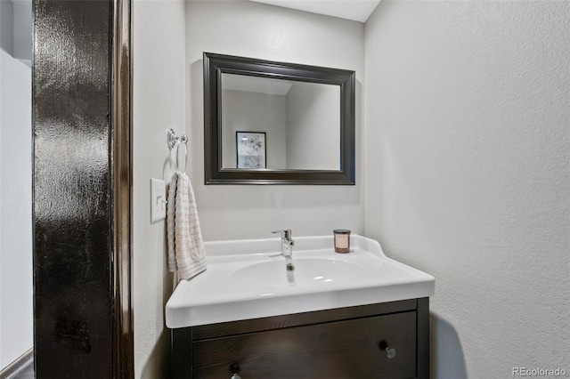 bathroom featuring a textured wall and vanity