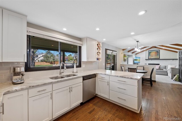 kitchen with stainless steel dishwasher, a peninsula, dark wood-type flooring, white cabinets, and a sink