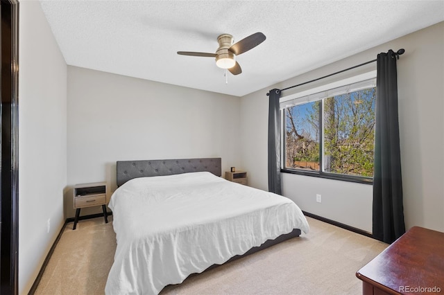 bedroom with baseboards, ceiling fan, light carpet, and a textured ceiling