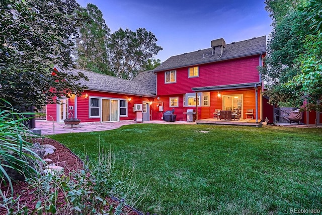 back house at dusk featuring a patio area and a yard