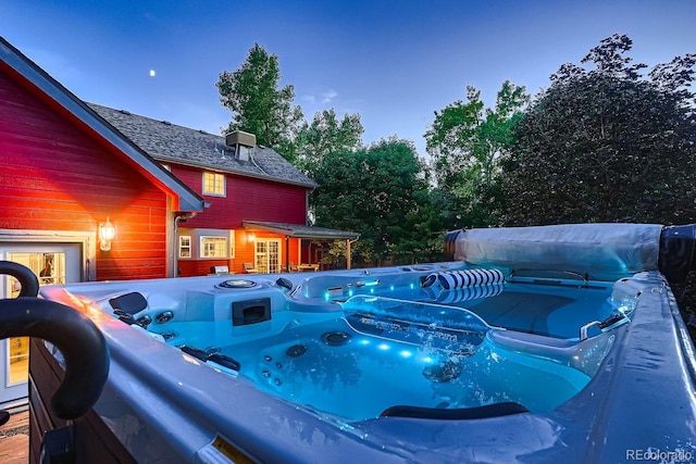 pool at dusk with a hot tub