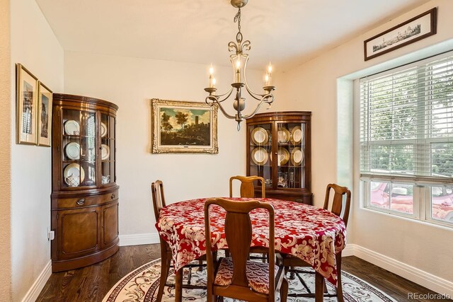 dining area with dark hardwood / wood-style floors and a notable chandelier