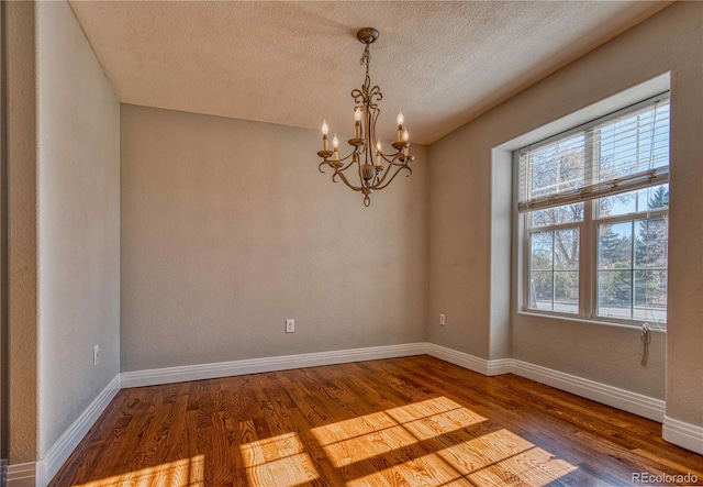 spare room featuring wood-type flooring, a textured ceiling, and a chandelier