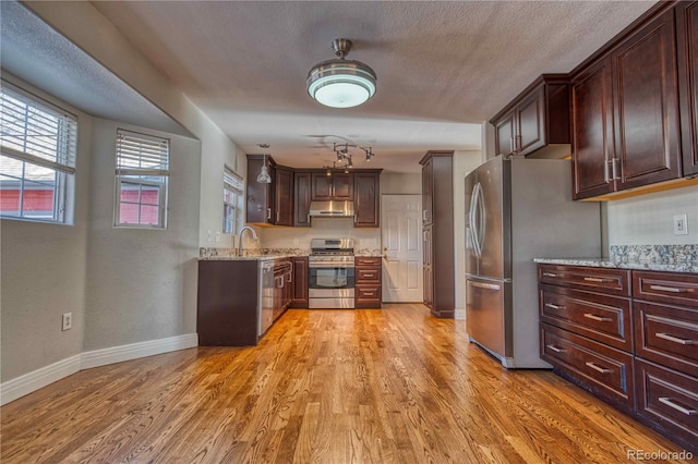 kitchen featuring sink, light hardwood / wood-style floors, light stone counters, and stainless steel appliances