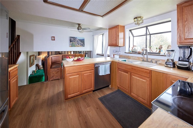 kitchen with dark wood-style flooring, a peninsula, light countertops, a sink, and dishwasher