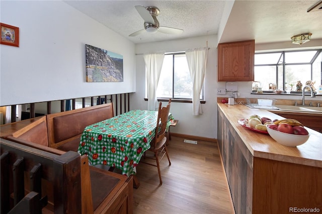 dining room featuring visible vents, baseboards, a textured ceiling, a ceiling fan, and light wood finished floors