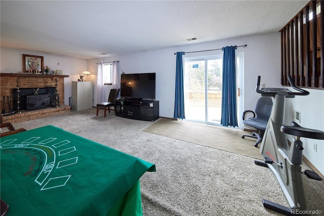 carpeted living area featuring visible vents, a textured ceiling, and a brick fireplace