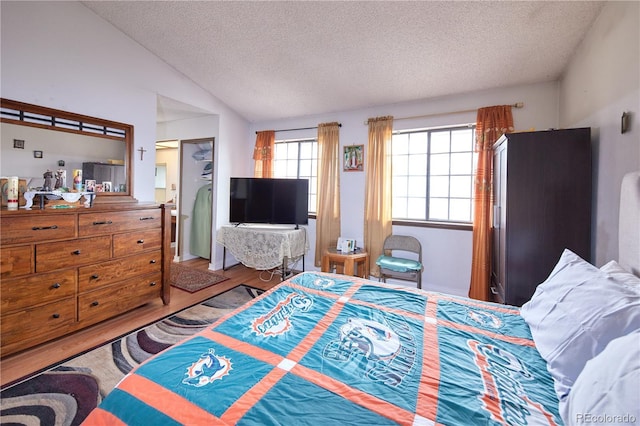 bedroom featuring vaulted ceiling, a textured ceiling, and wood finished floors