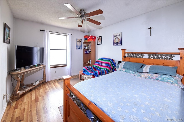 bedroom featuring baseboards, a textured ceiling, ceiling fan, and wood finished floors