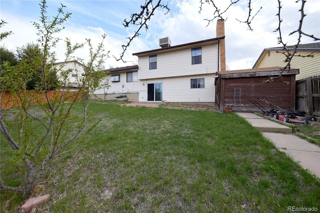 back of property with a fenced backyard, a yard, and a chimney