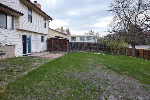 view of yard featuring a storage unit, a fenced backyard, and an outdoor structure