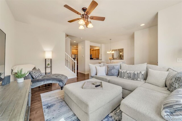 living room with hardwood / wood-style flooring and ceiling fan with notable chandelier