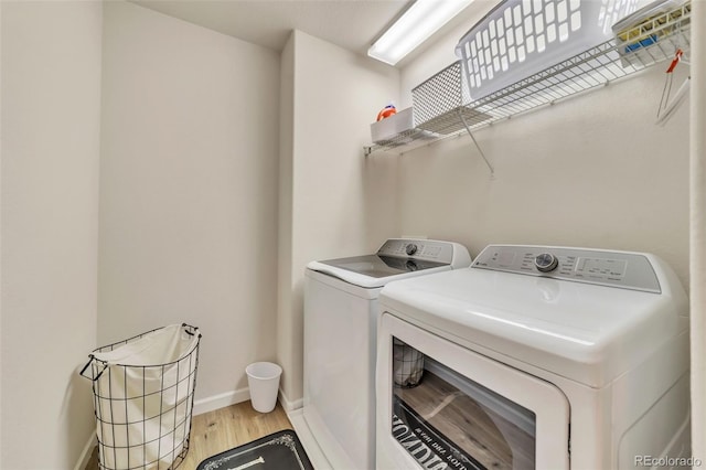 laundry room with washing machine and clothes dryer and light hardwood / wood-style flooring