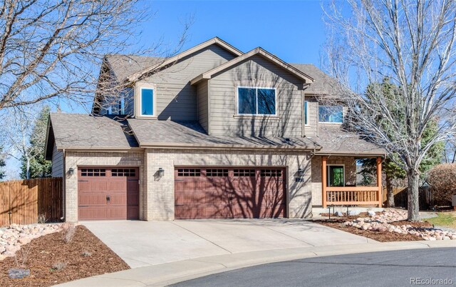 view of front of house with concrete driveway, roof with shingles, fence, an attached garage, and brick siding