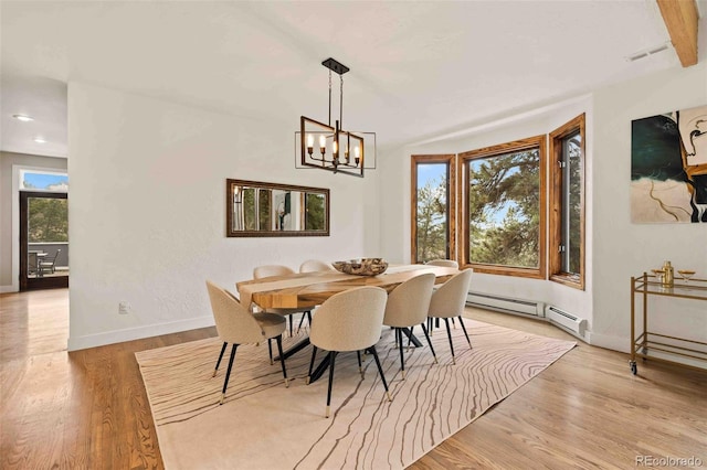 dining space with baseboards, baseboard heating, light wood-style flooring, and a notable chandelier