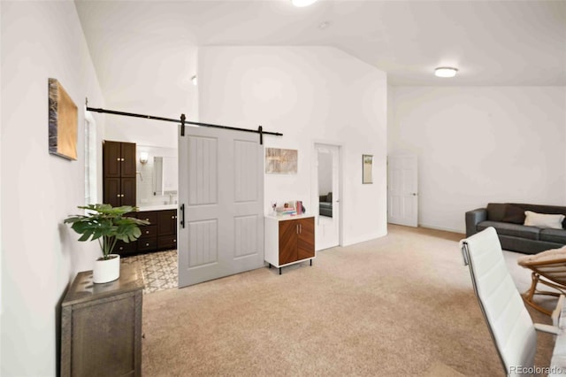 living room with high vaulted ceiling, light colored carpet, and a barn door