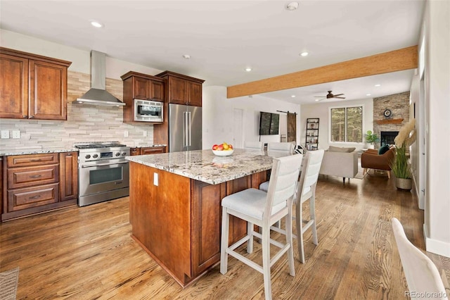 kitchen featuring a center island, light wood-style flooring, wall chimney exhaust hood, and high end appliances
