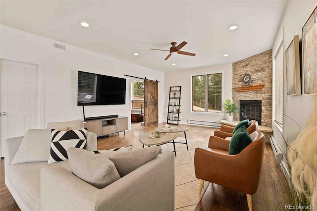 living area with visible vents, recessed lighting, a barn door, a baseboard heating unit, and a ceiling fan
