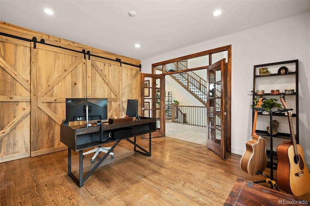 office space with recessed lighting, baseboards, a barn door, and wood finished floors
