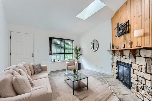 living room with a stone fireplace, lofted ceiling with skylight, and hardwood / wood-style flooring