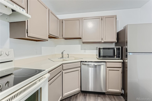 kitchen with appliances with stainless steel finishes, dark hardwood / wood-style flooring, gray cabinetry, extractor fan, and sink