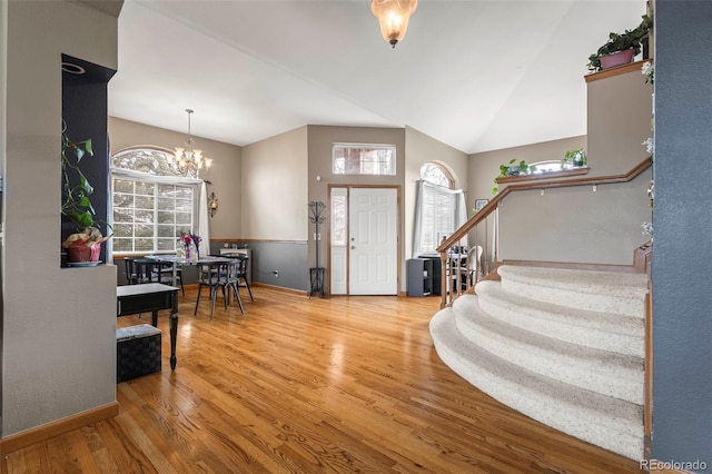 foyer featuring a notable chandelier, wood-type flooring, and vaulted ceiling