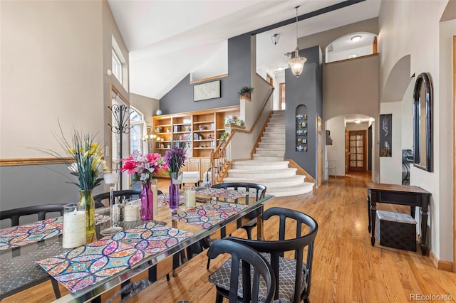 dining space featuring high vaulted ceiling and light hardwood / wood-style floors