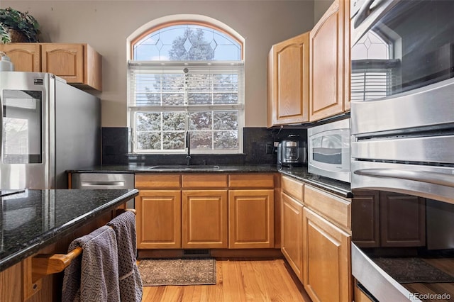 kitchen with sink, backsplash, stainless steel appliances, and light wood-type flooring