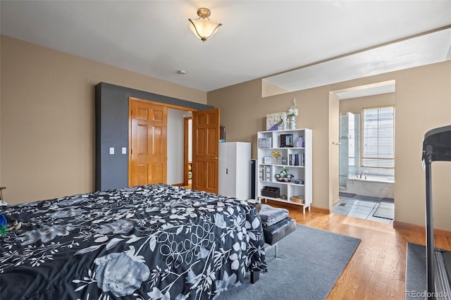 bedroom featuring hardwood / wood-style flooring and ensuite bath