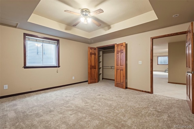 unfurnished bedroom with light colored carpet, ceiling fan, and a tray ceiling