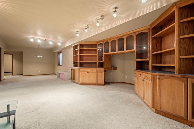 unfurnished living room with rail lighting, light carpet, and built in desk