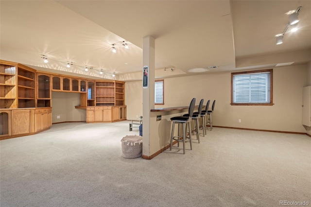 kitchen featuring a kitchen bar, rail lighting, and carpet