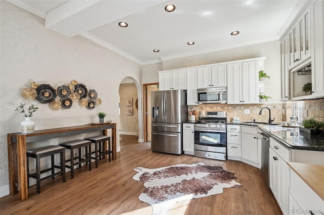 kitchen featuring appliances with stainless steel finishes, dark countertops, a sink, and wood finished floors