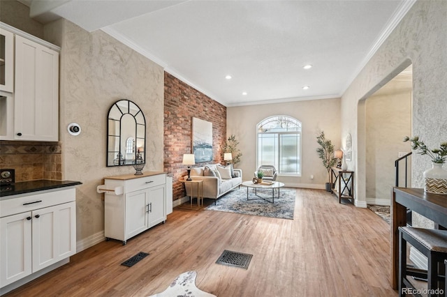 living area with light wood finished floors, visible vents, baseboards, crown molding, and recessed lighting