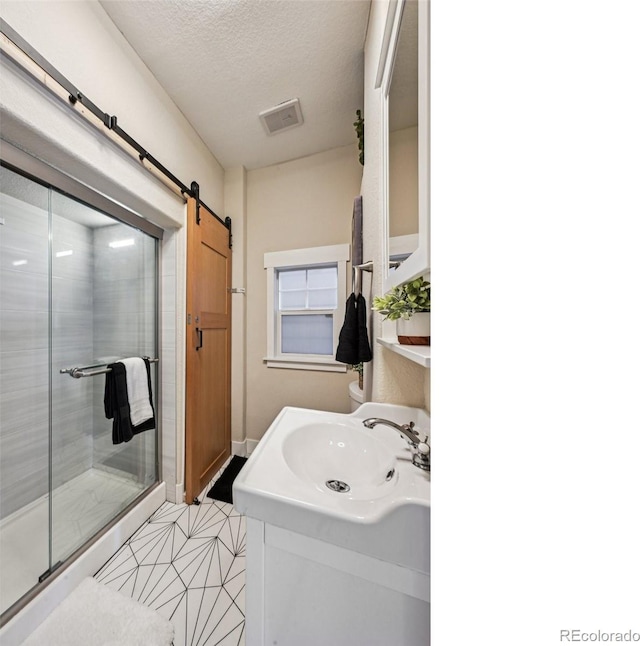 full bath with a textured ceiling, visible vents, a stall shower, and vanity