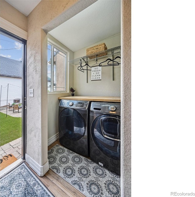 clothes washing area featuring washer and dryer, laundry area, baseboards, and wood finished floors