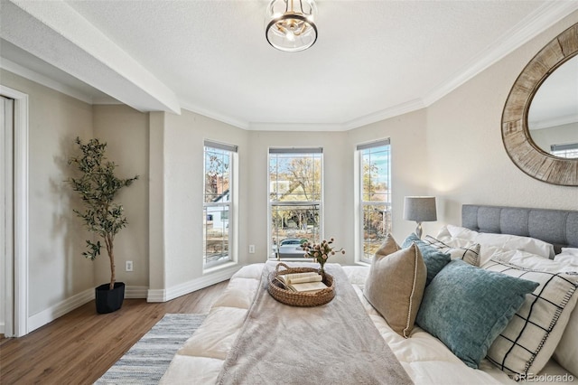 bedroom featuring ornamental molding, a textured ceiling, baseboards, and wood finished floors