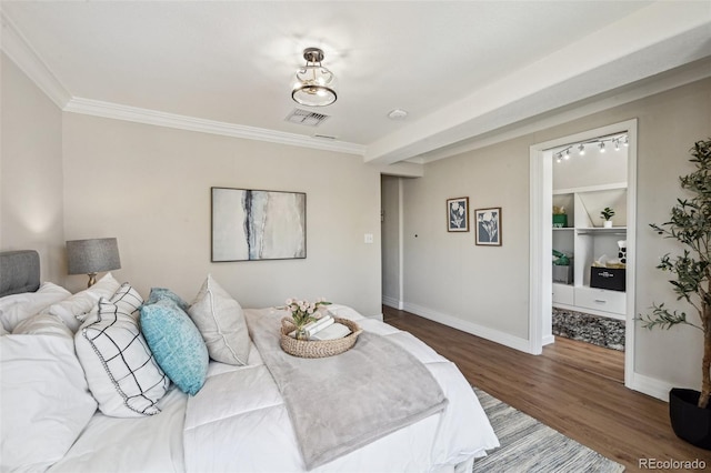 bedroom with baseboards, visible vents, wood finished floors, and ornamental molding