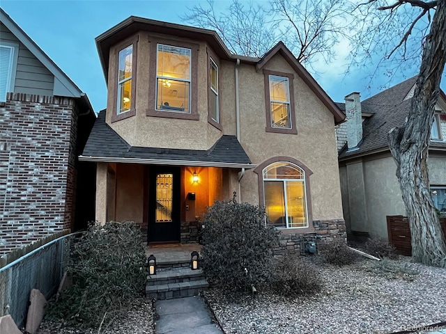 view of front of home with stone siding, a shingled roof, and stucco siding