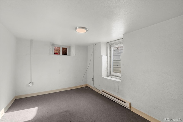 carpeted empty room featuring a textured ceiling and baseboard heating