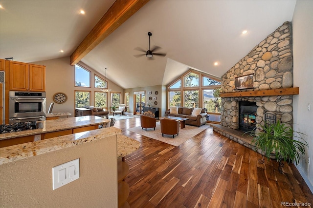26452 Wolverine Trl, Evergreen, CO 80439 - living room featuring ceiling fan, wood-type flooring, a stone fireplace, beamed ceiling, and high vaulted ceiling