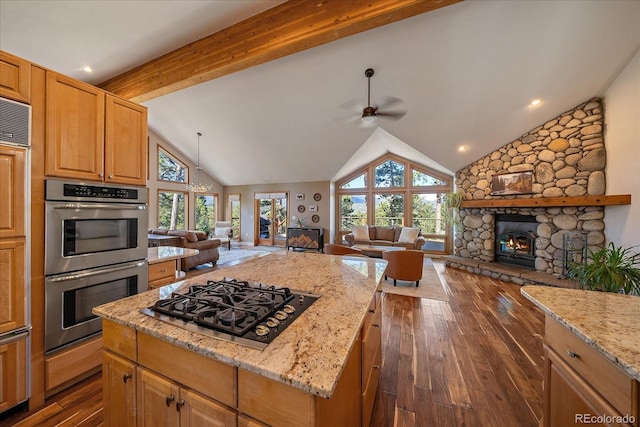 26452 Wolverine Trl, Evergreen, CO 80439 - kitchen with a stone fireplace, black gas cooktop, open floor plan, stainless steel double oven, and ceiling fan