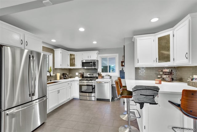 kitchen featuring light countertops, decorative backsplash, stainless steel appliances, and a sink