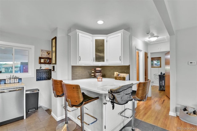 kitchen with white cabinetry, kitchen peninsula, dishwasher, and plenty of natural light